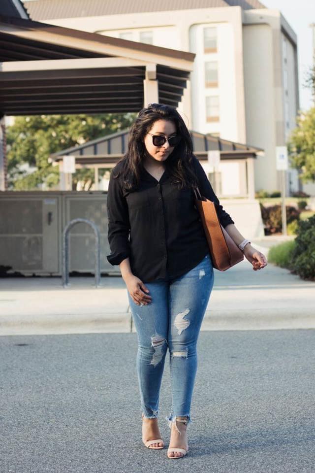 Combinación de blusa negra y jeans rasgados para outfit semi formal en mujeres maduras